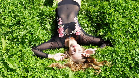 美丽的年轻女子躺在草地上。清新自然的夏季概念。从顶部看。