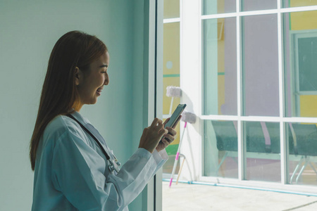 一位亚洲医生正在玩智能手机。