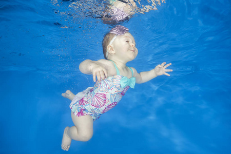 Little girl learns to swims underwater. Baby swimming underwater