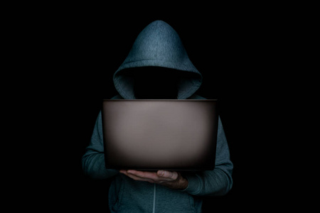 黑底黑底,手上拿着笔记本电脑的匿名黑客照片