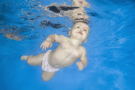 Little baby learns to swims underwater. Baby swimming underwater