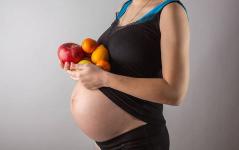 怀孕和健康的有机营养。孕妇持有新鲜维生素水果，自由空间。文本的位置。期望与健康的概念。