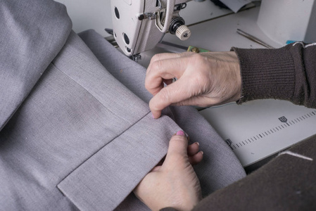 高级时装师,以缝纫机为背景,用高级布料缝制衣服,由服装制造业的专业