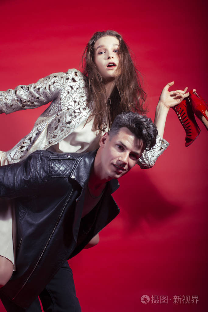 男女女在红色背景下手捧派对鞋摆造型,时尚风格让人眼前一亮照片-正版