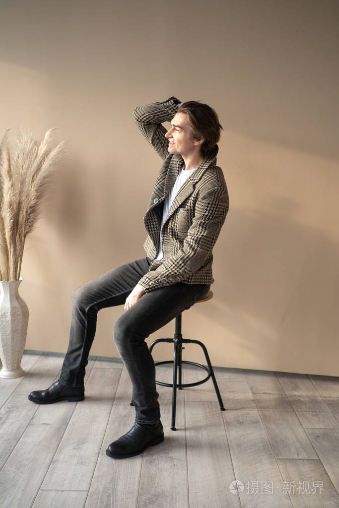 高个子英俊的男人坐在吧台的椅子上在阳光下从窗户照进来