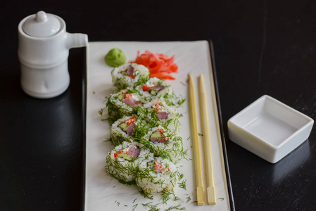 三文鱼寿司卷放在一个白色盘子里，上面有姜芥末和酱油。日本料理。
