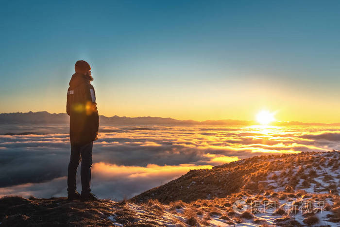 一个人站在山上日落时云端之上