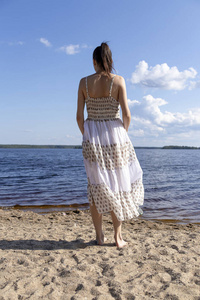 Young caucasian girl stands on the beach against the background 