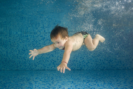 Little boy swim underwater in the swimming pool. It floats and s