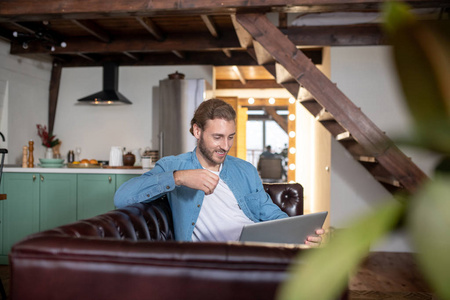 Emotional young man texting with his partner using a laptop