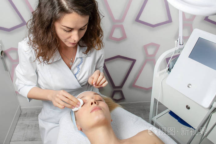 年轻迷人的美容师在美容院为女性客户做抗衰老程序面膜和脱皮美容专家