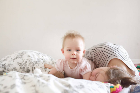 Sweet little baby girl lying on tummy on bed with her mother in 