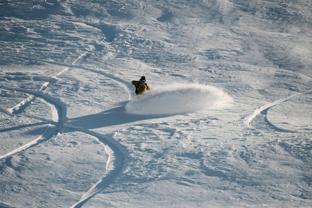 穿着运动服的滑雪板运动员在滑雪板上的雪地上滑行并留下痕迹照片