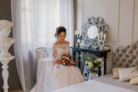 美丽幸福的新娘在一个有结婚花束的房间里。
