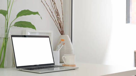 Cropped shot of minimal workspace with blank screen laptop, coff