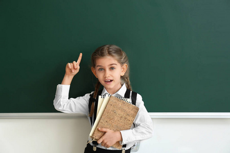 教室里，一个小女生举起食指靠近黑板
