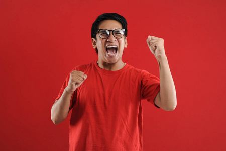 Young asian man happy and excited expressing winning gesture. 