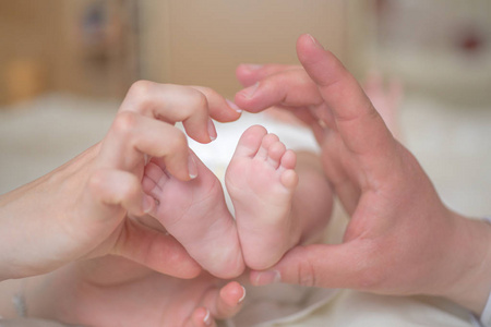 婴儿的脚托在父母的手上。爱的概念，家庭的爱。