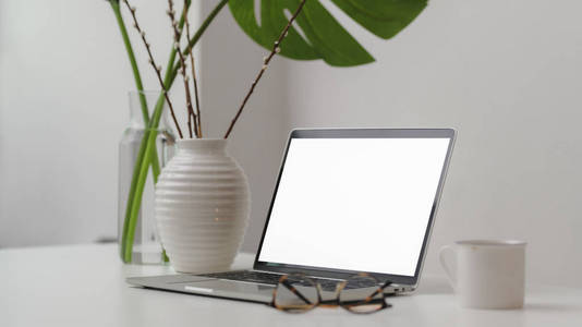 Cropped shot of trendy workspace with laptop, coffee cup, glasse