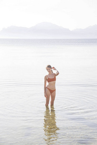 一个穿泳衣的女孩站在海里。意识和放松。