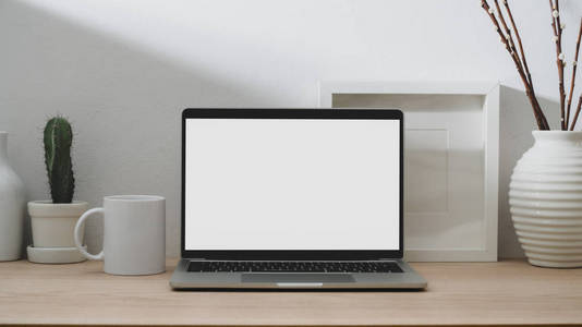 Close up view of modern workspace with blank screen laptop, coff