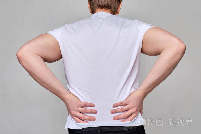 一个穿白色t恤的男人抓住了他的下背部腰痛脊椎痛骨质疏松症
