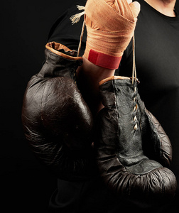 muscular athlete in a black uniform holds very old brown boxing 