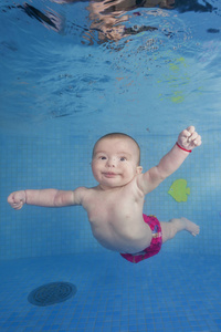 Little baby learns to swims underwater. Baby swimming underwater