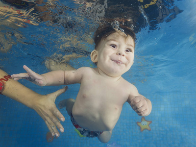 Little baby boy learning to swim underwater in a swimming pool, 