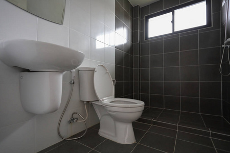 现代设计的小浴室，白色马桶，黑色瓷砖墙面和地板
