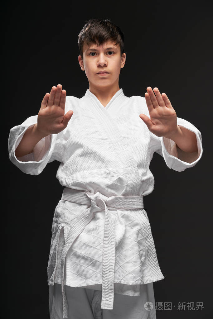 运动概念-一个穿着武术服装的青少年在深灰色背景下摆姿势,摄影棚拍摄