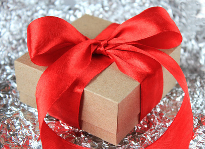 Closeup wrapped vintage gift box with red ribbon bow on silver 