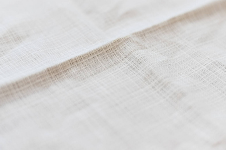 柔和的浅灰色自然亚麻织物，重点在于褶皱。褶皱的织物背景。选择性聚焦。特写视图