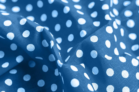 经典的蓝色圆点织物纹理。皱折的亮色棉布，背景印着白色圆圈。选择性聚焦。特写视图