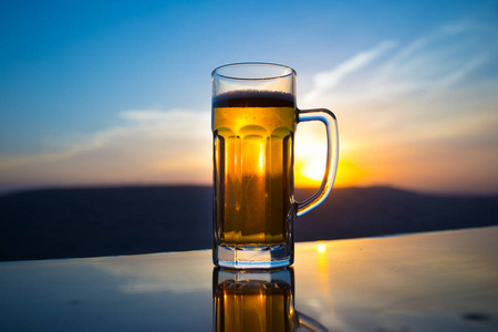 凉爽的夏季饮料概念.以阳光为背景的一杯生啤酒的特写镜头照片