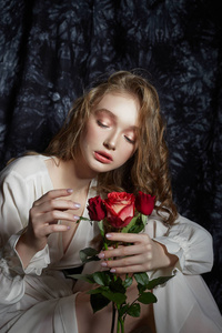 Beautiful spring girl is sitting on the floor with rose flowers 