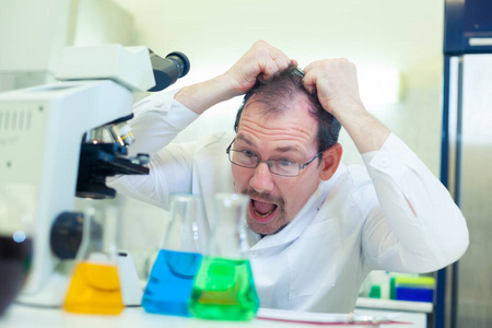 化学家疯了。一个疯狂的科学家在科学实验室里做实验。他用惊讶的目光仔细检查着烧瓶里的液体。他扯着头发。