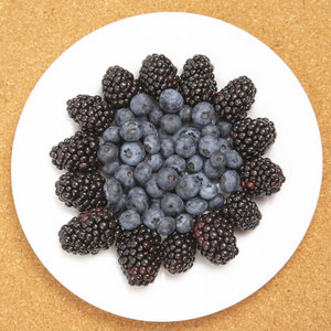 Blueberries and blackberries on a white plate. Vitamin and Diet 