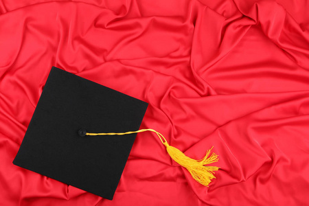 红色缎面背景上的毕业帽