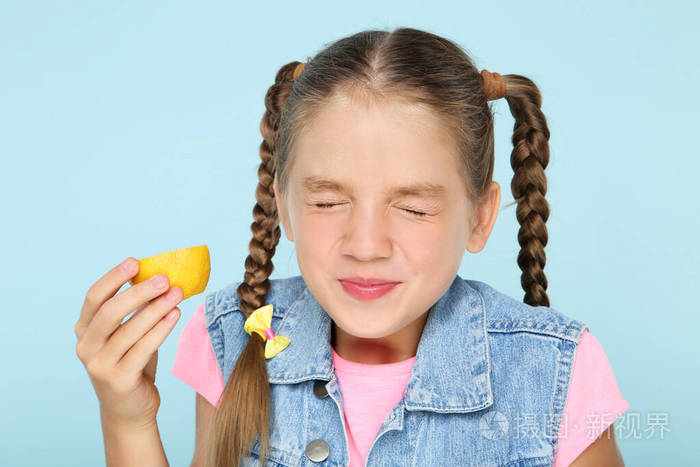 蓝色背景下吃柠檬水果的小女孩