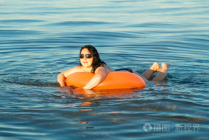 一个黑发女人在海里绕着游泳圈游泳