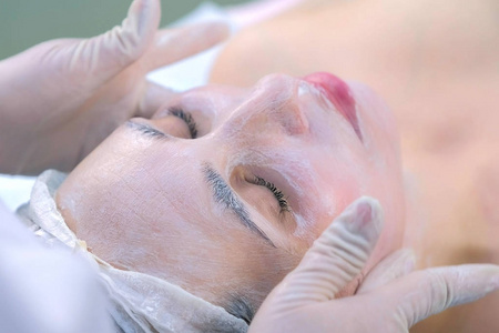 美容师用保湿面膜对女性进行面部按摩。