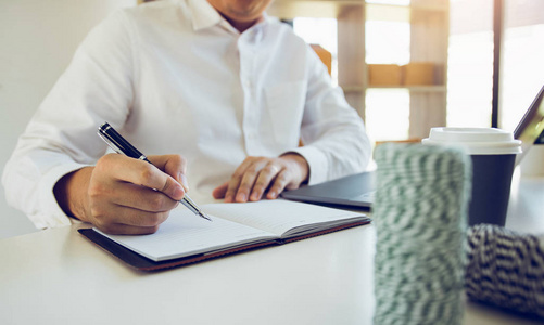 年轻的亚洲人在电脑上看书写字照片