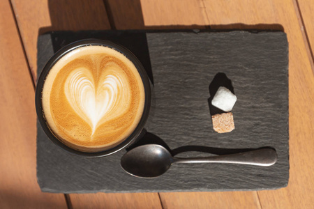 咖啡厅桌子上有心形泡沫的卡布奇诺咖啡