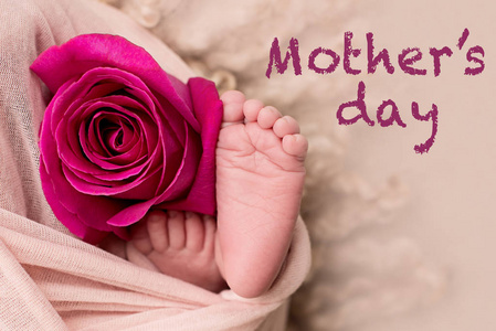 母亲节快乐。新生婴儿的脚上有粉红色的玫瑰花
