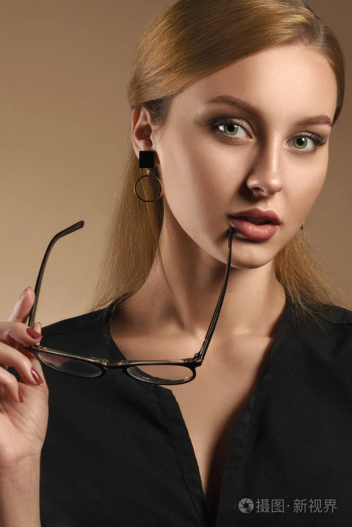 美女摘下眼镜穿黑色衬衫的垂直肖像