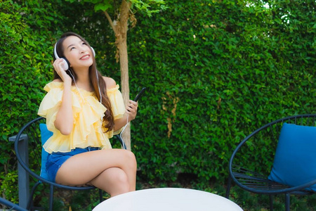 年轻的亚洲女人用智能手机和耳机给李