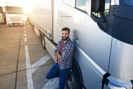 中年职业卡车司机交叉双臂站在他的卡车旁。运输服务。