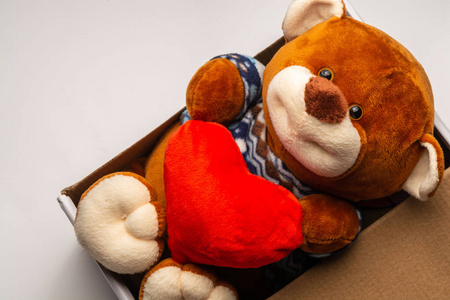 白色背景的泰迪熊在盒子里抱着一颗心