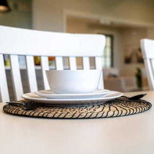 图为家庭餐桌上的方桌，白色餐具和圆形餐垫